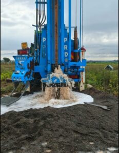 a drilling rig operating during borehole construction, with drill crew visible