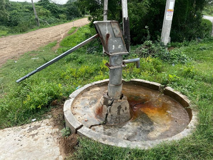 a community borehole or handpump in a rural East African setting, with water being drawn